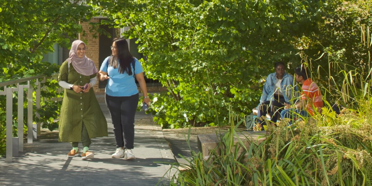 Students walking through greenery by the Great Hall